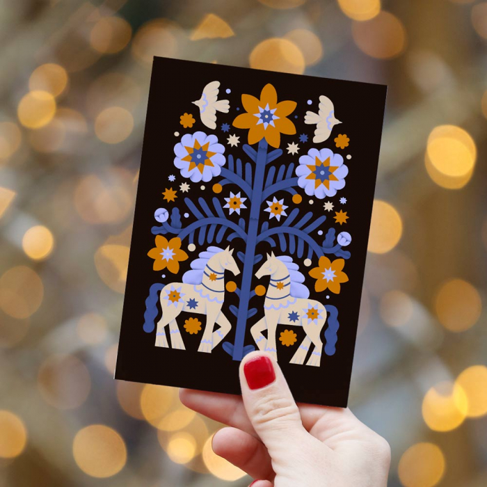 A folk horse card held up against festive lights
